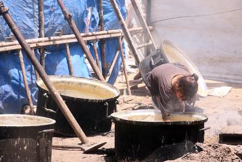 A young girl in Gaza trying to gather the remaining scraps of food from the cooking pot.